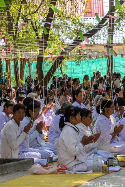 people sitting with white strings tied above them