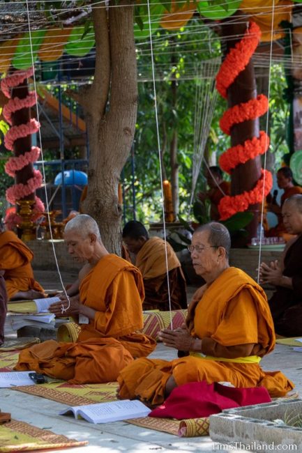 monks sitting with white strings tied above them