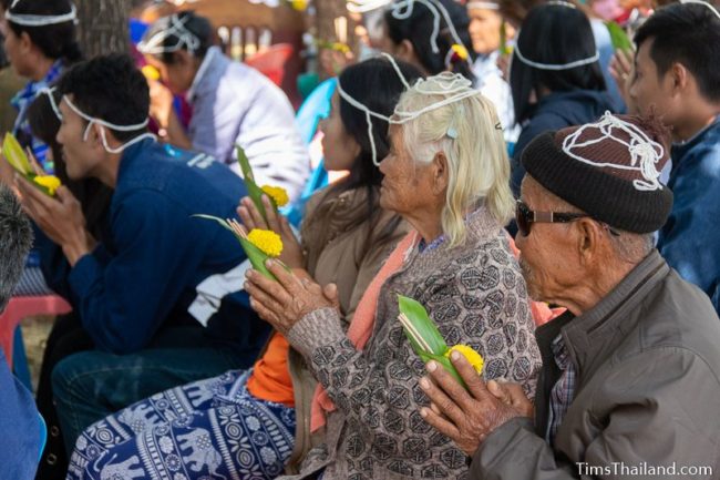 people with white string on their heads holding flowers