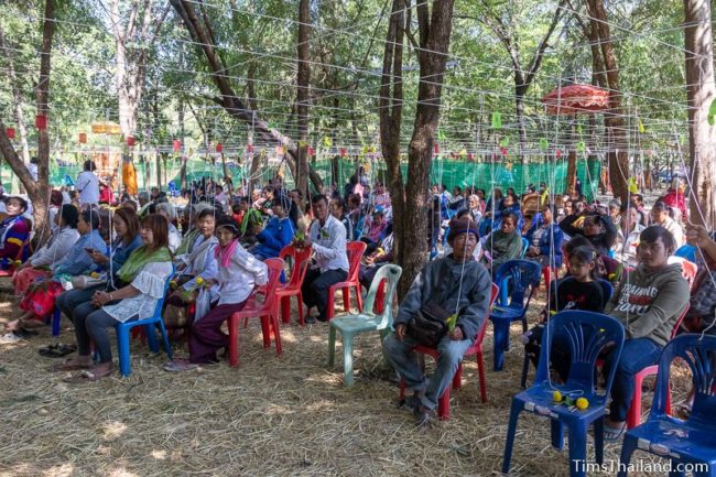 people sitting with white strings tied above them