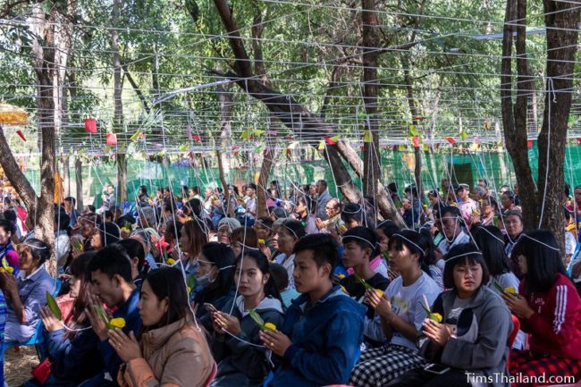 people sitting with white strings tied above them