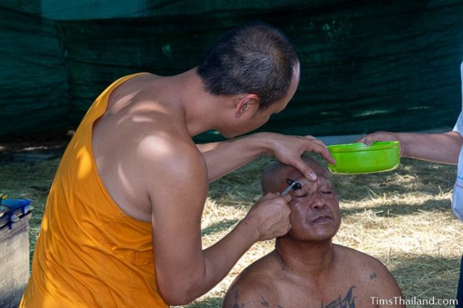 monk shaving a man's eyebrows