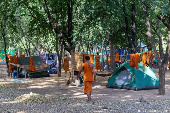 monks walking amidst tents