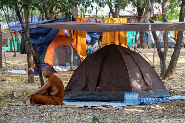 monk sitting next to his tent
