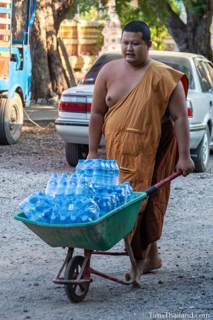 monk carrying bottles of water in a wheelbarrow