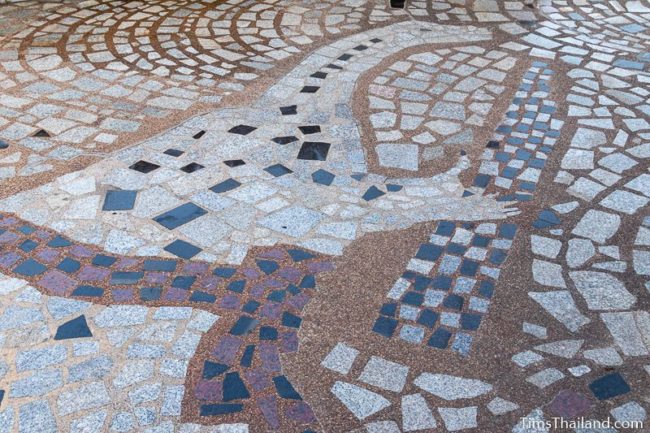 floor mosaic of dinosaur playing a kaen