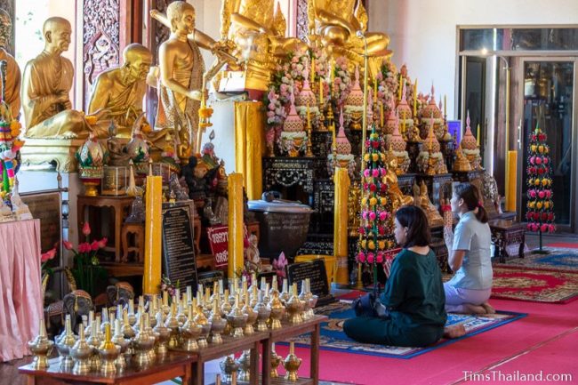 two women praying in front of a Buddha