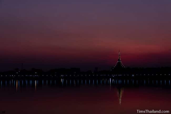 stupa seen from across a lake at sunset