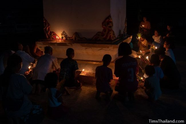 people putting candles around the base of a stupa