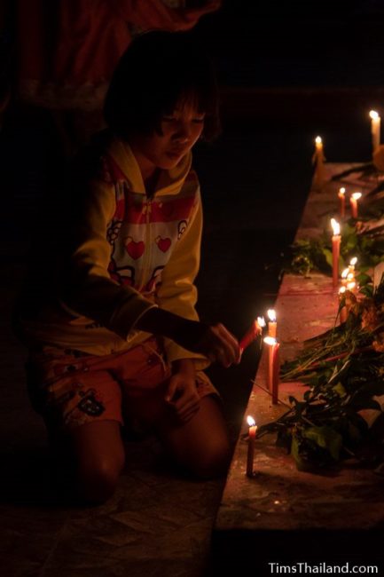 girl putting candles around the base of a stupa