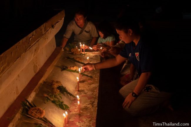 people putting candles around the base of a stupa