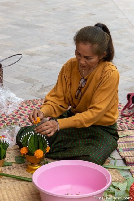 woman putting flower on top of a bai sii