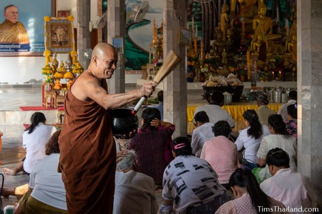 monk blessing people by splashing water