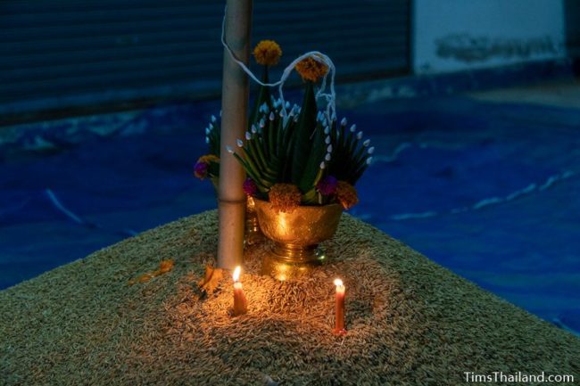 lit candles and bai sii on top of rice pile