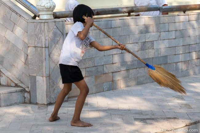 girl sweeping in front of temple