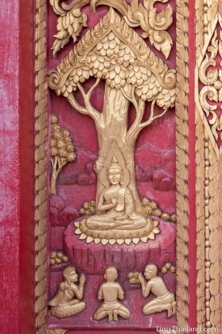 woodcarving of Buddha sitting under a tree.