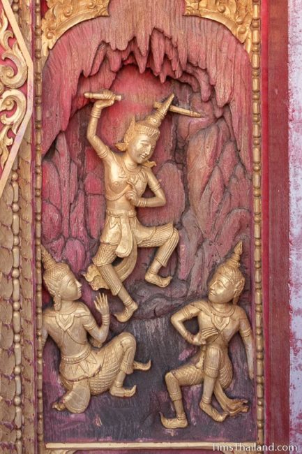 woodcarving of man threatening two others with a sword.