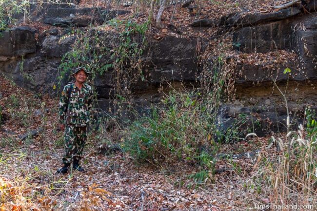 park ranger standing in front of a rock wall with cut marks