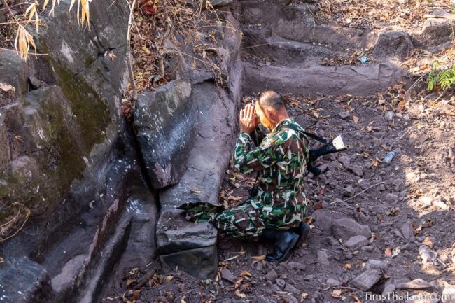 park ranger making offering at rock outcrop with blocks cut out of it