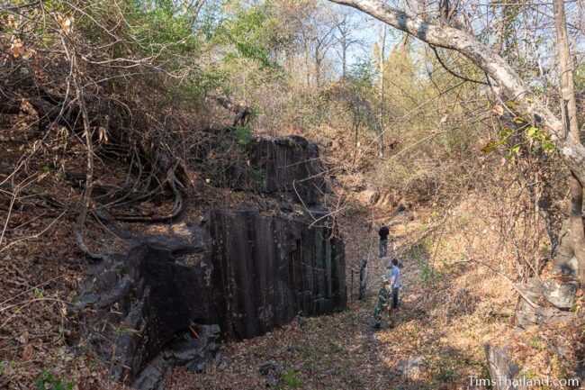 people looking at rock wall with cut marks