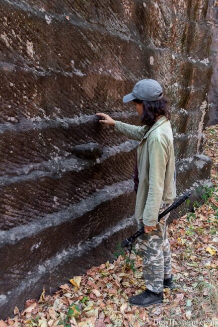 woman looking at rock wall with cut marks