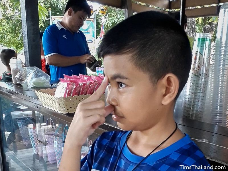 boy at coffee shop showing sign for farang