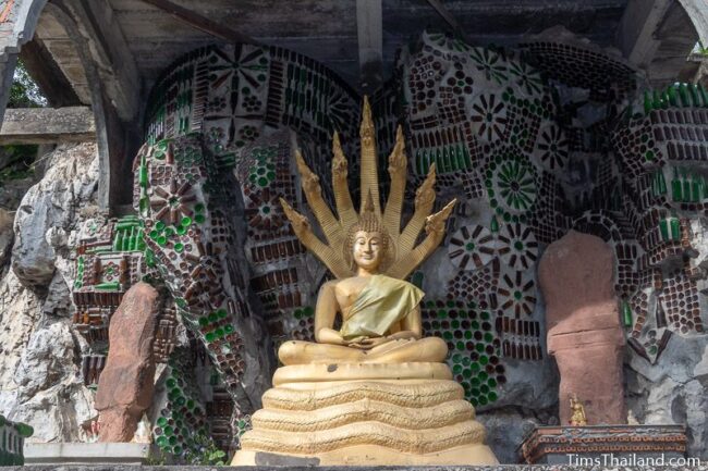 Buddha with bottle art behind it