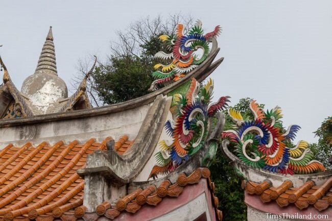 Chinese decoration on top of roof and a stupa in the background