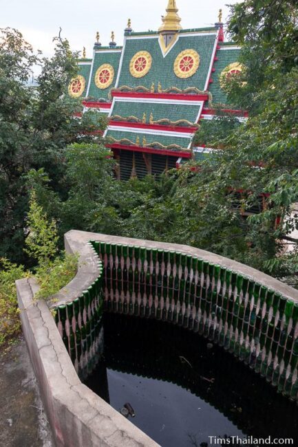 pond lined with bottles in front of ubosot