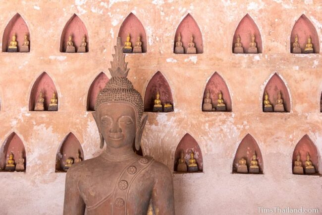 large Buddha in front of wall with smaller Buddhas in little alcoves