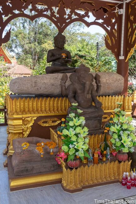 big stone slap, pedestal, and two sculptures in a shrine