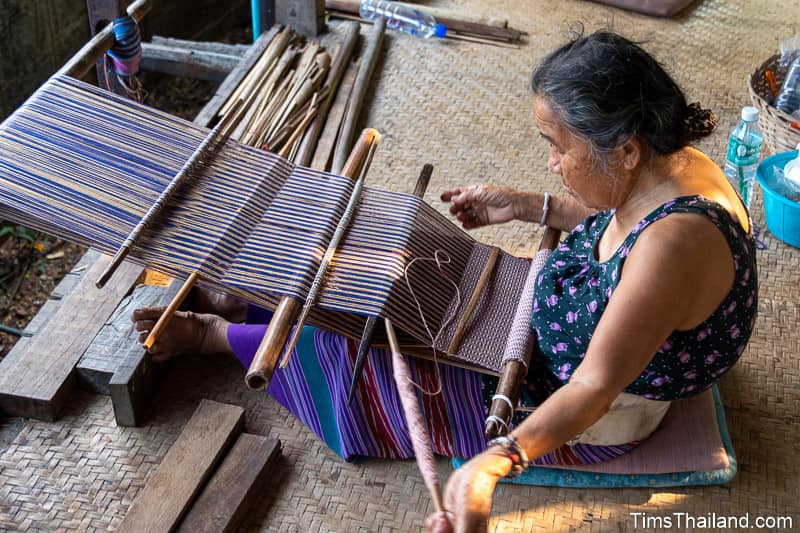 old woman weaving with backstrap loom