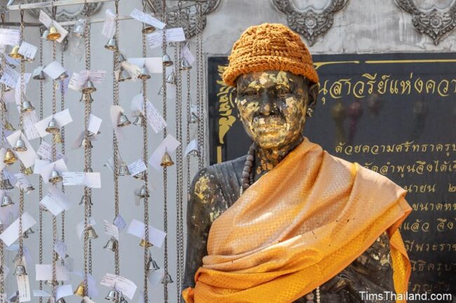 statue of monk nect to small bells