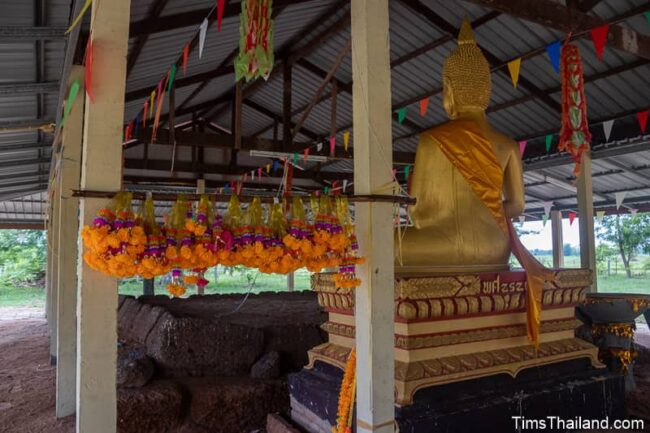 flower offerings next to Buddha in front of Khmer ruin