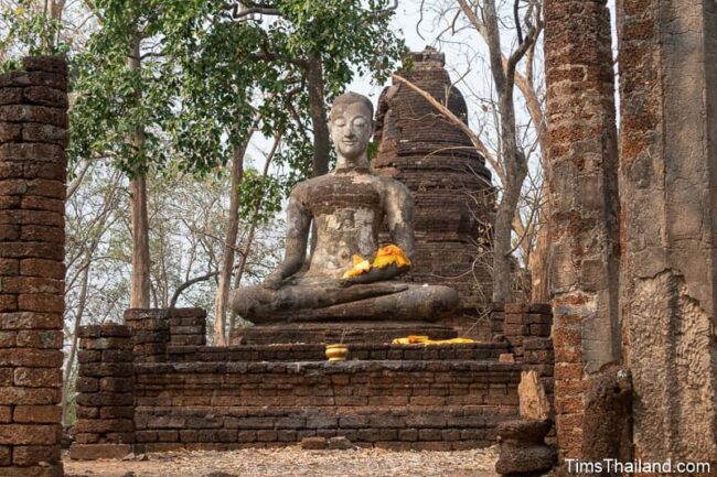 Buddha statue in front of ancient stupa