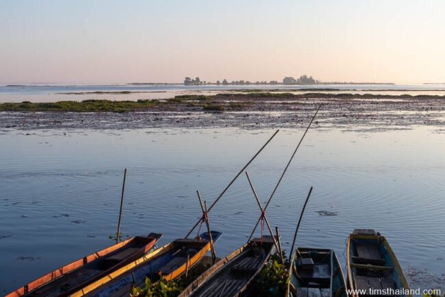 boats along shore of lake with island in the distance