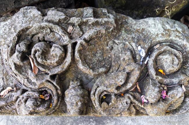 carving of a small head amidst vines