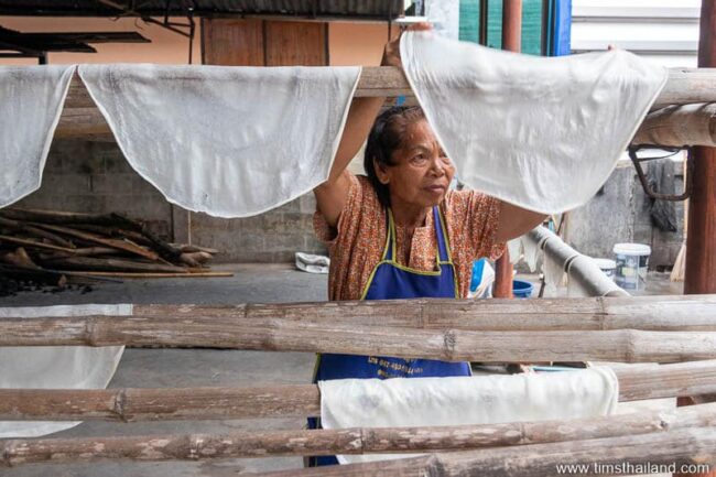 woman hanging sheets of uncut phimai noodles