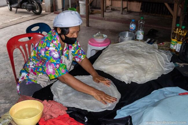 woman stacking sheets of uncut phimai noodles