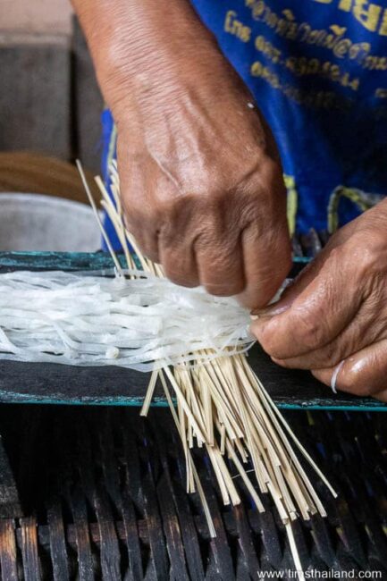 woman tying bundle of phimai noodles