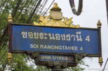 <b>Ranong city</b><br>At the center of the design is a ship's wheel around the reclining Buddha from Wat Waree Banprot, one of the province's most important temples. The birds on the sides are <i>hongsa</i>, swan-like birds from the mythical Himmapan Forest. Nobody could tell me if the bell-shaped top represents anything or not. I thought maybe it was supposed to be a lighthouse, but was told that it was not this. Street sign from Ranong city