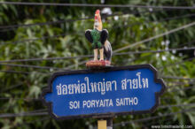 street sign with chicken statue on top